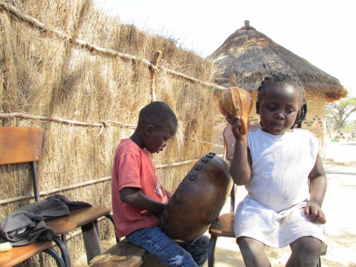 A boy playing mbira and a girl playing hosho